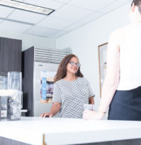 Two Carr Maloney staff members having a conversation in the break room.