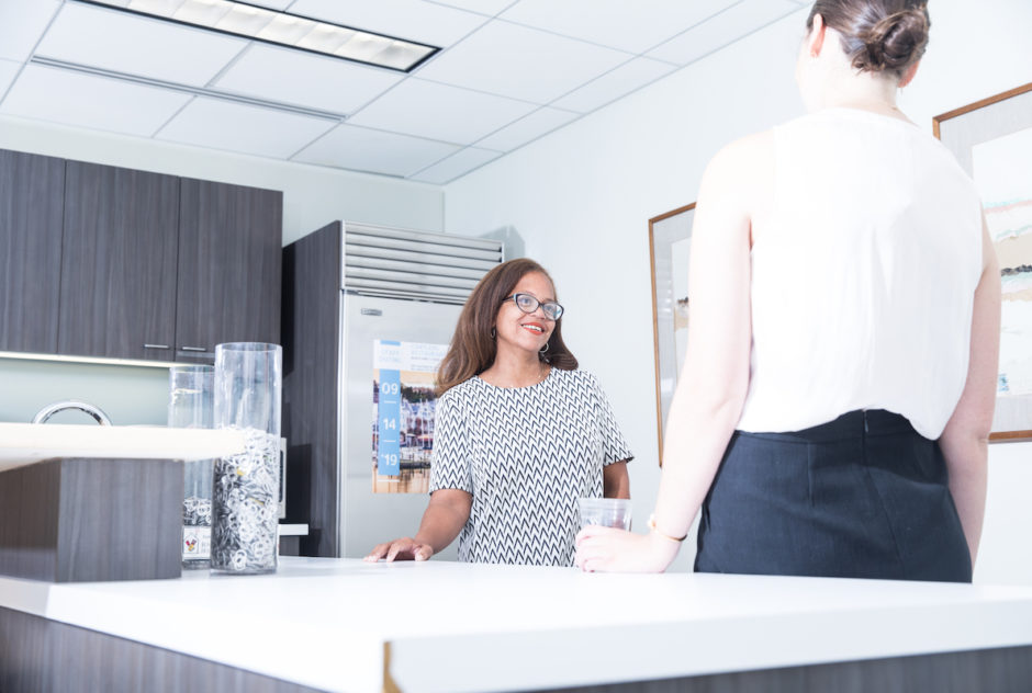 Two Carr Maloney staff members having a conversation in the break room.